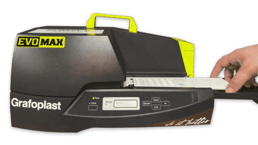 A hand inserts a plastic plate into a black and yellow EVOMAX Thermal Printer featuring control buttons and a display screen on the front panel.